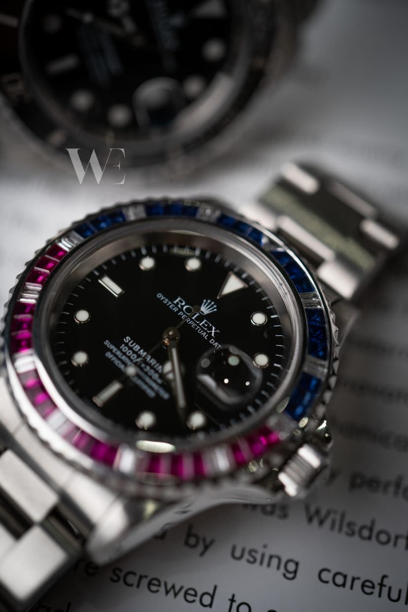 Rolex Submariner Date à lunette sertie de pierres rouges, bleues et blanches, sur un livre